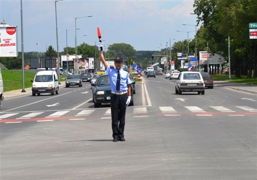 Вертикално подигната рака на униформираниот полициски службеник со палка во дланката (како на сликата), значи: