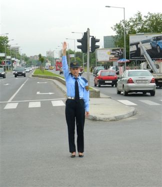 Polici zyrtar i uniformuar gjatë rregullimit të komunikacionit në udhëkryq (si në fotografinë):