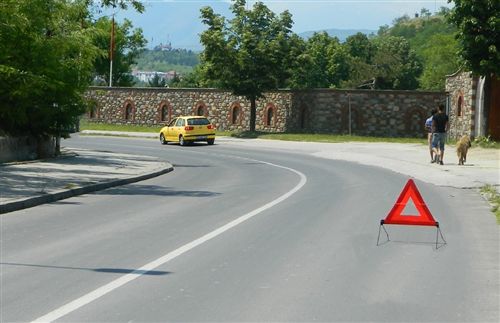 Shenja e posaçme me të cilën shënohet automjeti i ndalur në vend jo mirë të dukshëm, jashtë vendbanimit (si në fotografi) vendoset në rrugë, pas automjetit të ndalur: