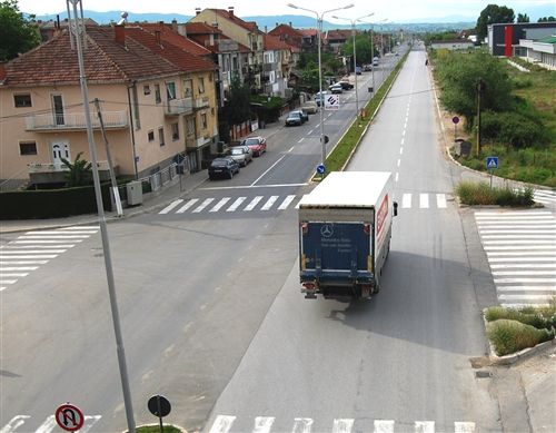 Shoferi i automjetit transportues të mallrave, ku masa më e madhe e lejuar e së cilës është më e madhe se 3.500 kg, kur qarkullon në rrugë publike në vendbanim (si në fotografinë), në të cilën ekzistojnë më së paku dy korsi komunikacioni për lëvizje në të njëjtën kahe: